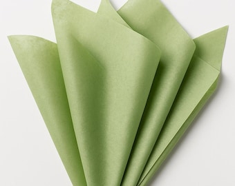 Puede incluir: Una pila de papel de seda verde salvia doblado en forma triangular. El papel tiene una textura fina y semitranslúcida, dispuesto en varias capas superpuestas que crean bordes afilados y puntiagudos en la parte superior y una base estrecha.