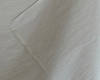 May include: Multiple sheets of thin, semi-translucent light gray tissue paper layered on top of each other. The paper has a smooth, matte texture with subtle creases and folds visible across the surface, showing a light and airy quality.