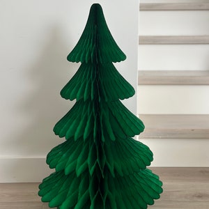 Könnte beinhalten: Ein grüner Weihnachtsbaum aus Papierwaben. Der Baum besteht aus mehreren Schichten Papier, die gefaltet und geschnitten werden, um eine dreidimensionale Form zu erzeugen.