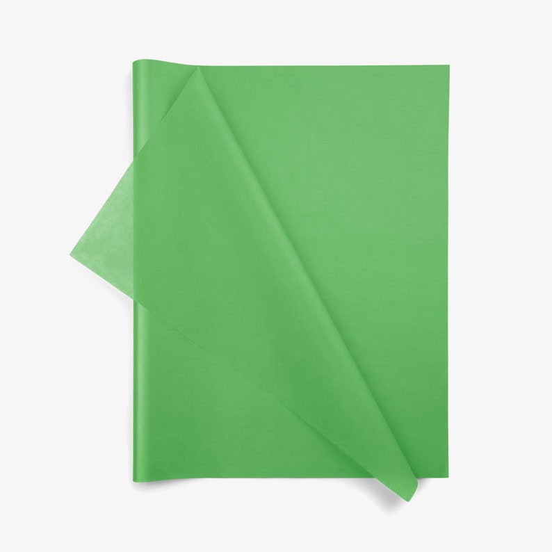 May include: A rectangular sheet of bright green tissue paper with a smooth, semi-translucent texture. The paper is folded diagonally across the center, creating a triangular flap that reveals a slightly lighter shade of green where it overlaps.