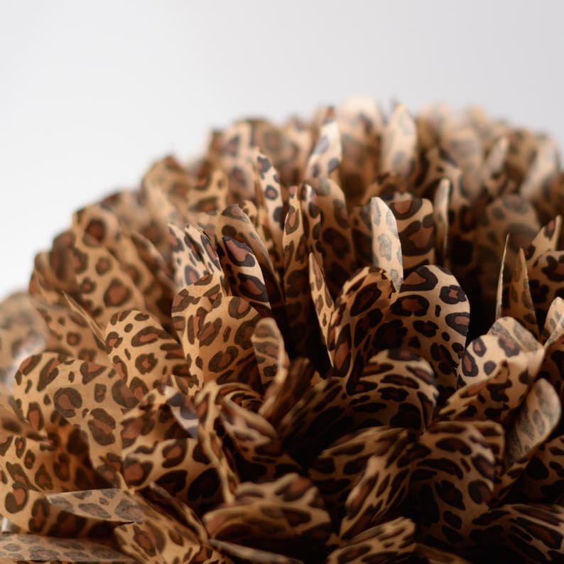 K&ouml;nnte beinhalten: Nahaufnahme eines braunen und beigen Papierpompoms mit Leopardenmuster.