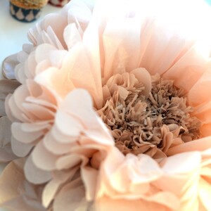May include: A large, peach-colored tissue paper flower with a brown center. The flower is made of many layers of tissue paper and has a delicate, ruffled appearance.