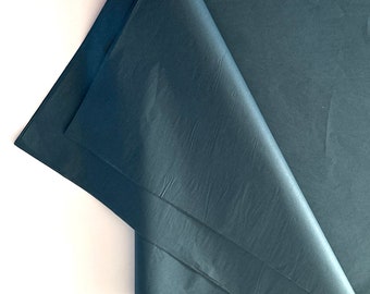 May include: A stack of dark charcoal gray tissue paper sheets with a smooth, thin, and slightly translucent texture. The top sheet is folded diagonally, revealing the layered structure and the matte finish of the dark gray paper material.