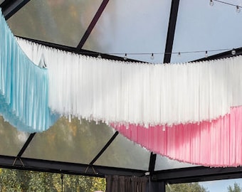 May include: A ceiling decorated with light blue, white, and pink fabric streamers hanging from a black metal frame.