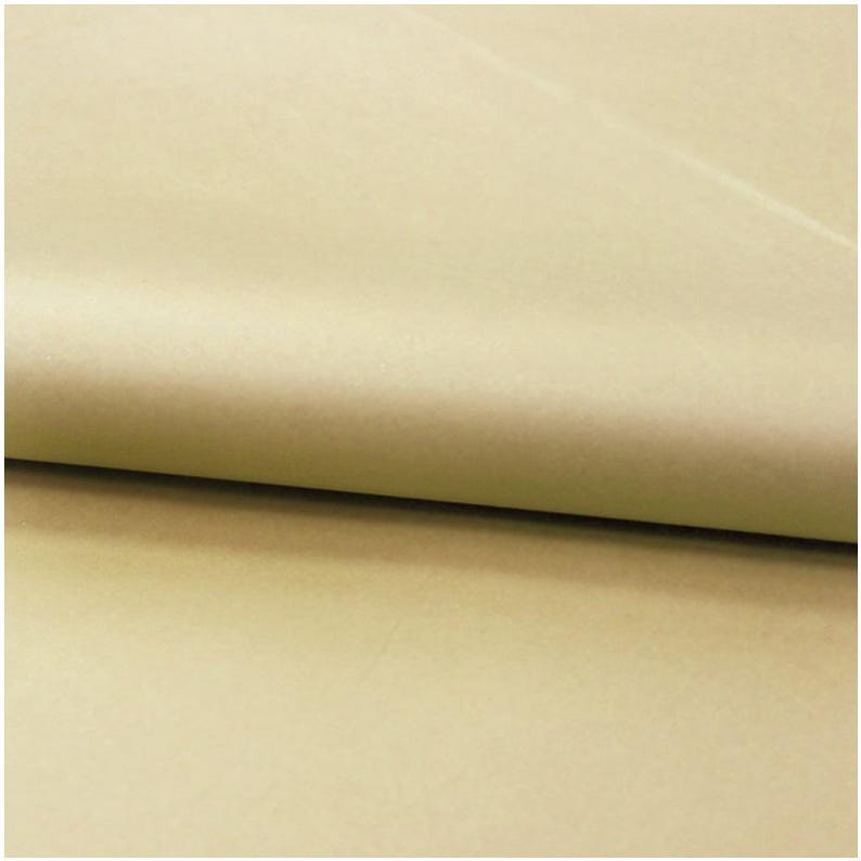 May include: A sheet of light tan, matte-finish paper folded over to create a soft, curved crease. The surface of the paper appears smooth and uniform in color, showing a consistent, neutral beige tone across the entire visible area of the material.