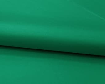Puede incluir: Una tela de color verde esmeralda sólido y vibrante doblada para crear un pliegue horizontal suave. El material tiene una textura lisa y mate con una coloración consistente, mostrando una superficie limpia sin patrones ni texturas.