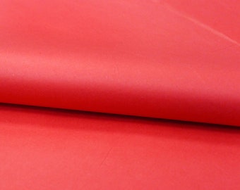 Può includere: Un singolo foglio di carta velina rosso vivace piegato per creare una piega morbida e curva al centro. La superficie della carta è liscia e opaca, mostrando un colore rosso solido e coerente in tutta l'area visibile dell'immagine.
