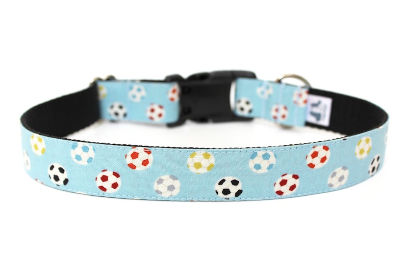 Peut inclure: Un collier pour chien bleu clair avec une boucle noire et un motif de ballons de football color&eacute;s.