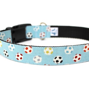 Peut inclure: Un collier pour chien bleu clair avec un motif de ballons de football color&eacute;s. Le collier a une boucle noire et un anneau en D argent&eacute;.