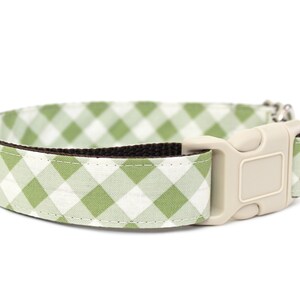 May include: A dog collar with a light green and white gingham pattern. The collar has a brown interior and a beige plastic buckle. The collar is designed for pets.