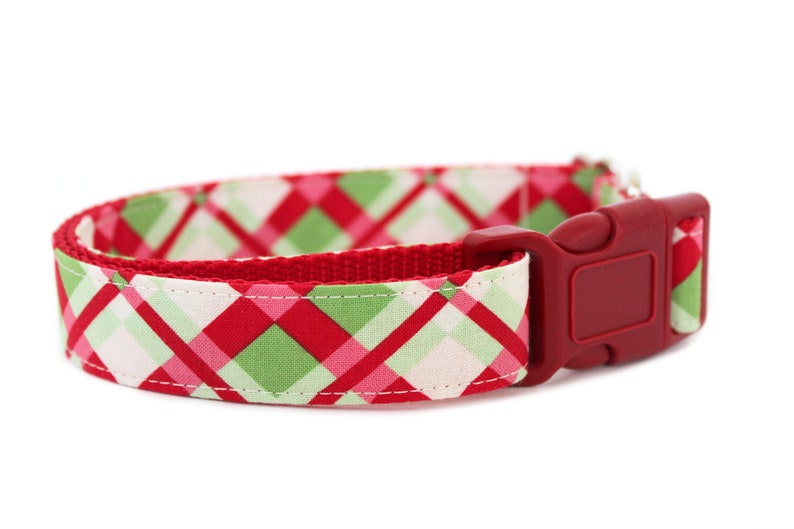 K&ouml;nnte beinhalten: Rotes, gr&uuml;nes und wei&szlig;es kariertes Hundehalsband mit einer roten Kunststoffschnalle.