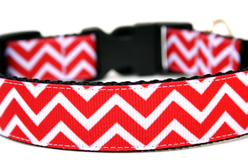 Puede incluir: Collar para perro con estampado de chevron rojo y blanco, hebilla negra y anilla en D de metal dorado.