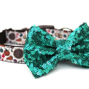 May include: A green sequin bow tie attached to a white and brown dog collar with a Thanksgiving-themed print featuring pumpkins, pies, and leaves.