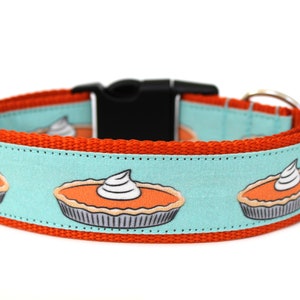 May include: Orange and turquoise dog collar with a repeating pattern of pumpkin pies with whipped cream on top.