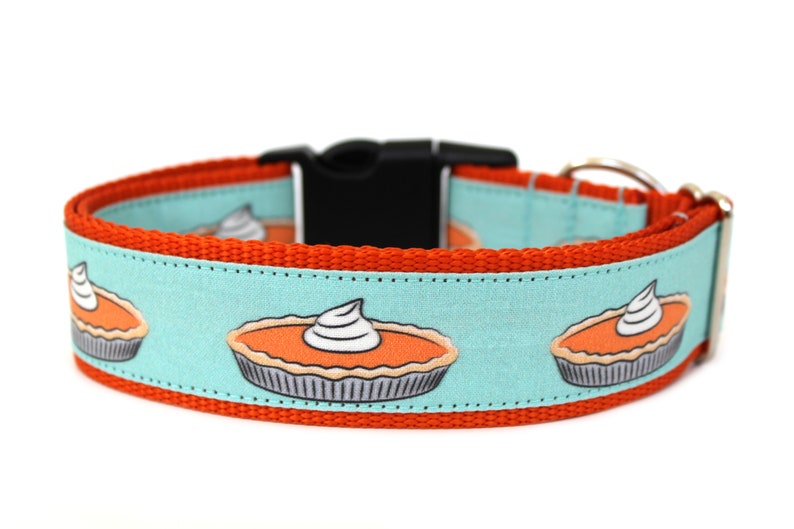 May include: Orange and turquoise dog collar with a repeating pattern of pumpkin pies with whipped cream on top.