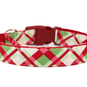 K&ouml;nnte beinhalten: Hundehalsband aus rotem, gr&uuml;nem und pinkem kariertem Stoff mit einer roten Kunststoffschnalle.