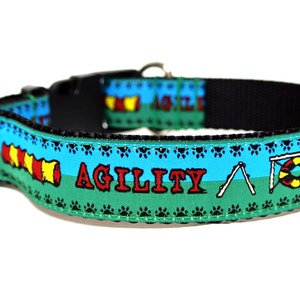 May include: A black dog collar with a colorful design featuring agility course obstacles. The collar has a green and blue background with the word "AGILITY" in red. Paw prints and agility equipment are also featured.