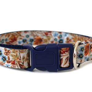 May include: A blue and white floral dog collar with a navy blue buckle and silver D-ring.
