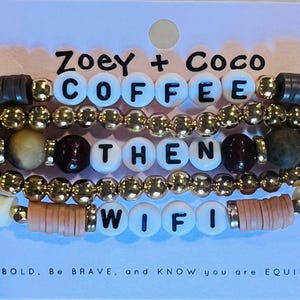 May include: Stacked beaded bracelets with the words "COFFEE THEN WIFI" spelled out in white letter beads. The bracelets feature gold, brown, and tan beads. The text "Zoey + Coco" is above the bracelets.