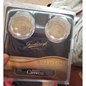 以下が含まれることがあります： Gainsborough Sonata Crystal ドアノブのパッケージ。ノブは金色で、多面的なデザインです。パッケージには「HALL & CLOSET」と「Interior Passage Non-Locking Door Knob」の文字が含まれています。