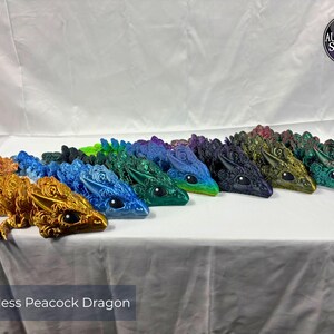May include: A collection of colorful Wingless Peacock Dragon figurines. The dragons are in various colors, including gold, blue, green, and purple. Each dragon has detailed features and a unique design. The text "Wingless Peacock Dragon" is at the bottom.