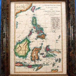 May include: An antique map of the East Indies, showing the islands of Borneo, Celebes, and the Philippines. The map is printed on aged paper and framed in a dark wood frame.