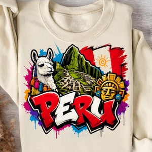 Könnte beinhalten: Ein cremefarbenes Sweatshirt mit einem Grafikdruck, der ein weißes Lama, die Ruinen von Machu Picchu, ein goldenes Sonnenemblem und das Wort PERU in fetten rot-weißen Buchstaben vor einem lebendigen, mehrfarbigen Farbspritzer-Hintergrund zeigt.
