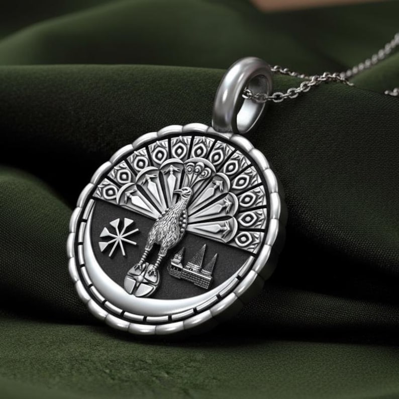 May include: Silver pendant necklace featuring a detailed peacock design within a circular frame. The pendant showcases a stylized peacock, a star, and architectural elements. The necklace has a delicate chain and a polished finish.