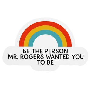 May include: A sticker featuring a rainbow design with red, orange, yellow, and blue arches. The text "BE THE PERSON MR. ROGERS WANTED YOU TO BE" is printed in black, centered below the rainbow.