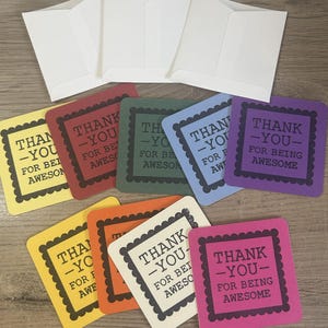 May include: A collection of colorful thank you cards with matching white envelopes. The cards are square with a scalloped border and the words "Thank You For Being Awesome" printed in black. Colors include yellow, red, green, blue, orange, and pink.