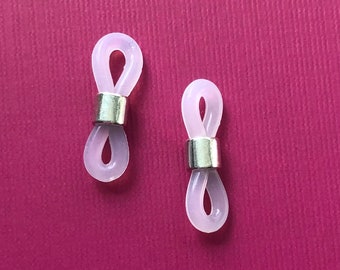 Puede incluir: Dos soportes de cordón de gafas de plástico transparente de color rosa claro en forma de bucle infinito con detalles metálicos plateados.