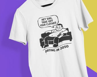 May include: White t-shirt with a black graphic of a person on a couch holding a remote control. A speech bubble says, "Hey Siri, take off your clothes." The text "Dating in 2050" is below the graphic.