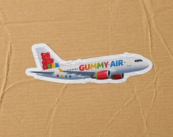 May include: A white airplane sticker featuring the text GUMMY AIR in multicolored letters on the fuselage. The tail fin displays a large red gummy bear alongside smaller green, yellow, and blue gummy bears. Additional small gummy bears are visible on the wing.