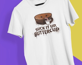 May include: White t-shirt featuring a cartoon peanut butter cup with a smiling face and a drink with a straw. The text "SUCK IT UP, BUTTERCUP" is printed below the graphic in a distressed font.