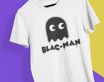 May include: A white short-sleeve t-shirt featuring a black spray-painted ghost graphic with two white circular eyes. Below the ghost, the text BLAC-MAN is printed in a black, dripping, spray-paint style font on the center of the chest.
