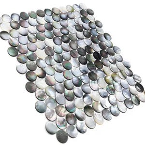 Può includere: Un foglio di piastrelle a mosaico composto da numerosi elementi ovali e iridescenti. Le piastrelle mostrano una gamma di colori, tra cui bianco, grigio e nero, con una finitura brillante e madreperlacea. La disposizione crea una superficie decorativa strutturata.