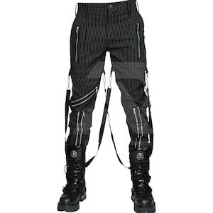 Könnte beinhalten: Schwarz-weiß gestreifte Hose mit mehreren silbernen Reißverschlüssen und Hosenträgern. Die Hose wird mit schwarzen Lederstiefeln mit Metallakzenten kombiniert. Der Stil ist edgy und alternativ.