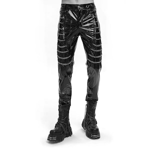 Może przedstawiać: Czarne, błyszczące spodnie ze sztucznej skóry ze srebrnymi łańcuszkami po bokach. Spodnie mają klasyczny krój z pięcioma kieszeniami i prostą nogawką. Modelka ma na sobie czarne buty na platformie z detalami łańcuszków.