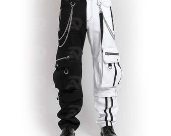 May include: Two-tone black and white trousers with multiple pockets, zips, and silver chain details. The design features a black left leg and a white right leg, offering a modern, edgy aesthetic. The trousers are a unique fashion statement.