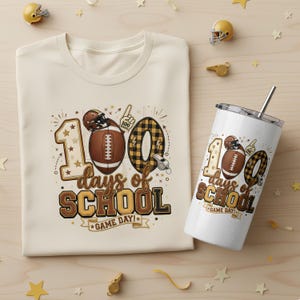 May include: A cream-colored t-shirt and a white tumbler with a football theme. The shirt and tumbler both feature the text "100 days of school" with football graphics. The tumbler has a silver lid and a straw.