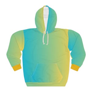 Puede incluir: Una sudadera con capucha con un diseño degradado. Los colores van del amarillo al turquesa, con un interior blanco en la capucha. Los puños son amarillos y la parte delantera tiene un bolsillo tipo canguro. El cordón es blanco.