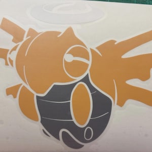 Pode incluir: Um autocolante recortado com uma criatura estilizada laranja e cinzenta semelhante a um inseto. O design tem uma estética de desenho animado com formas arredondadas e uma paleta de cores simples. O autocolante está num fundo branco.