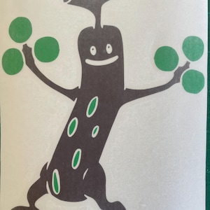 May include: A dark brown, anthropomorphic tree-like character decal with a smiling face, two Y-shaped branches at the top, and two arms extended outward. The figure features green circular leaves on its hands and green oval spots on its body.
