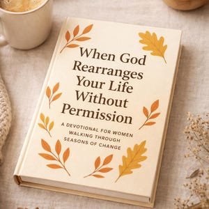 May include: A hardback book, "When God Rearranges Your Life Without Permission", with autumnal leaf designs. A coffee cup, a bowl of acorns, and a pen are on a neutral-toned surface.