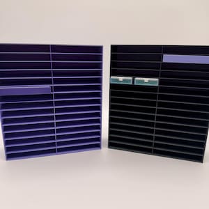 May include: Two organizer shelves, one lavender and one black, each with multiple horizontal slots. The lavender shelf has a lavender accent, and the black shelf has a lavender accent and two small, light green accents.