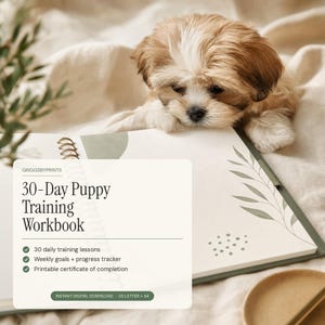 a small brown and white puppy resting its head on an open book, with a plant visible in the background.
