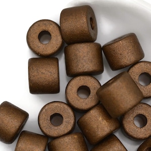May include: A close-up of a pile of brown wooden beads. The beads are round with a hole in the center. They are perfect for jewelry making or other crafts.