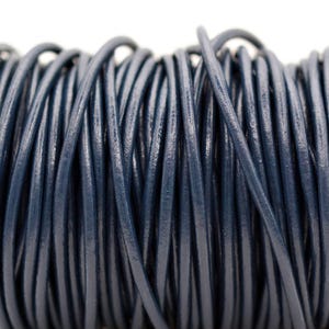 May include: A spool of navy blue leather cord. The cord is tightly wound, revealing a cylindrical shape. The leather appears smooth and has a slight sheen, suggesting a high-quality material. The cord is suitable for jewelry making and crafting.