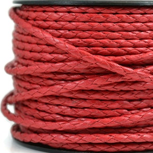May include: A spool of bright red braided cord wrapped in multiple layers. The cord features a consistent woven texture throughout its length, wound tightly around a black cylindrical core, creating a uniform and dense cylindrical shape.