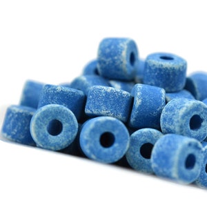 May include: A pile of blue ceramic beads with a speckled finish. The beads are round with a hole in the center.